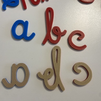 Letras de plástico coloridas em azul, vermelho e bege sobre superfície branca