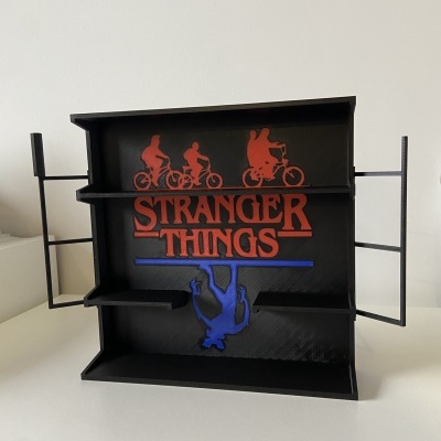 Expositor preto com logo Stranger Things e silhuetas vermelhas e azuis