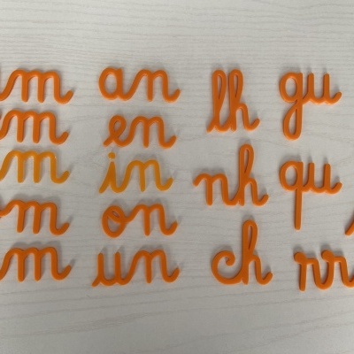 Letras plásticas laranja em pares organizadas sobre superfície branca