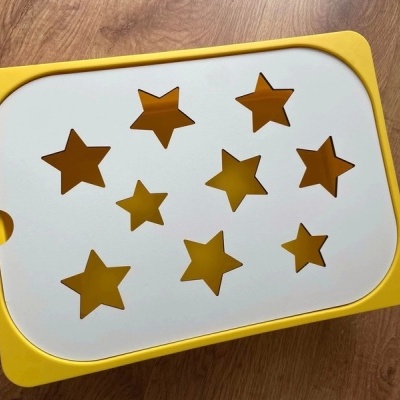 Caixa organizadora amarela com tampo branco e recortes em forma de estrelas