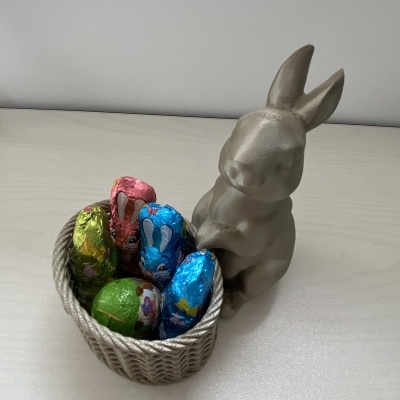 Coelho decorativo com cesto de ovos de chocolate coloridos