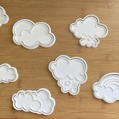 Moldes de silicone branco com formas de nuvens, sol, raio e arco-íris sobre madeira clara