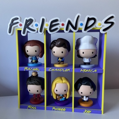 Bonecos colecionáveis da série FRIENDS em suporte com nomes das personagens.