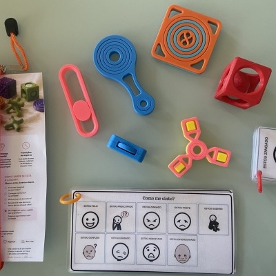 Brinquedos fidget coloridos e cartão com expressões faciais em português