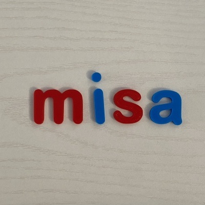 Letras de plástico coloridas formando a palavra 'misa' em superfície de madeira clara