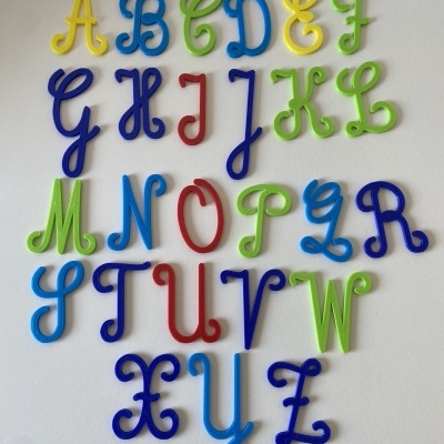 Letras do alfabeto coloridas em plástico cursivas sobre superfície branca