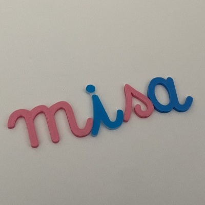 Letras decorativas rosa e azul formando a palavra 'misa' numa superfície branca
