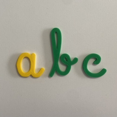 três letras de plástico coloridas a, b e c numa superfície branca
