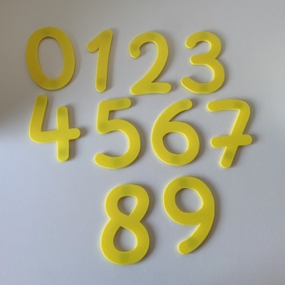 Números de espuma amarelos de 0 a 9 sobre fundo branco