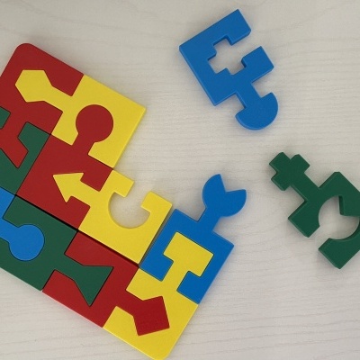 Peças coloridas de puzzle em plástico parcialmente montadas sobre uma mesa clara