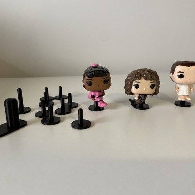 Três figuras Funko Pop com vários suportes de plástico preto em fundo branco.