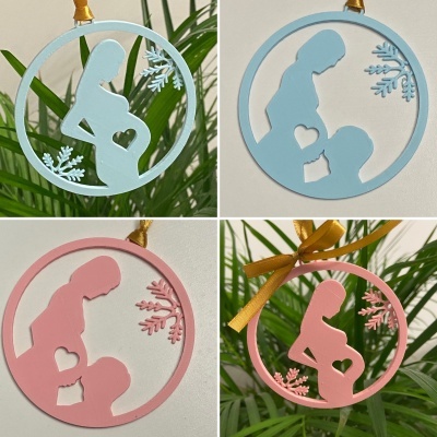 Ornamentos decorativos redondos com silhuetas de mulher grávida e criança, em azul claro e rosa, com detalhes de coração e flocos de neve.