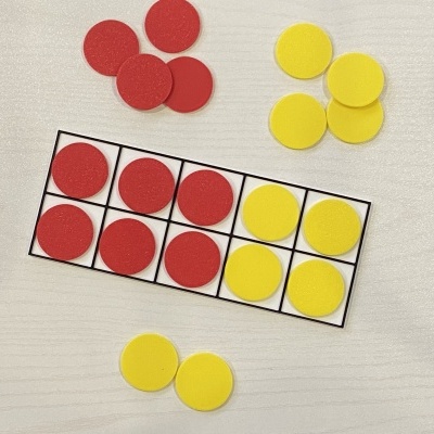 Círculos de plástico vermelhos e amarelos organizados numa grade preta sobre uma superfície clara