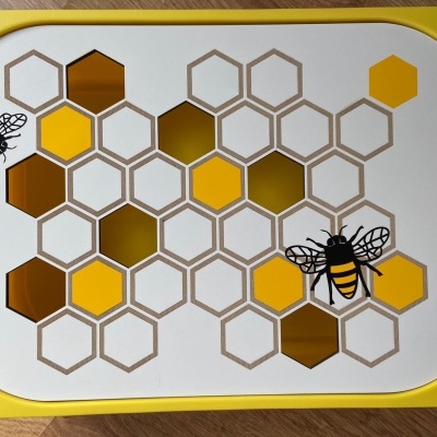 Tabuleiro em amarelo e branco com padrão de colmeia e abelhas