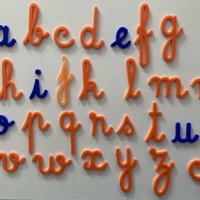 Letras de plástico laranja e azul em alfabeto minúsculo sobre fundo branco