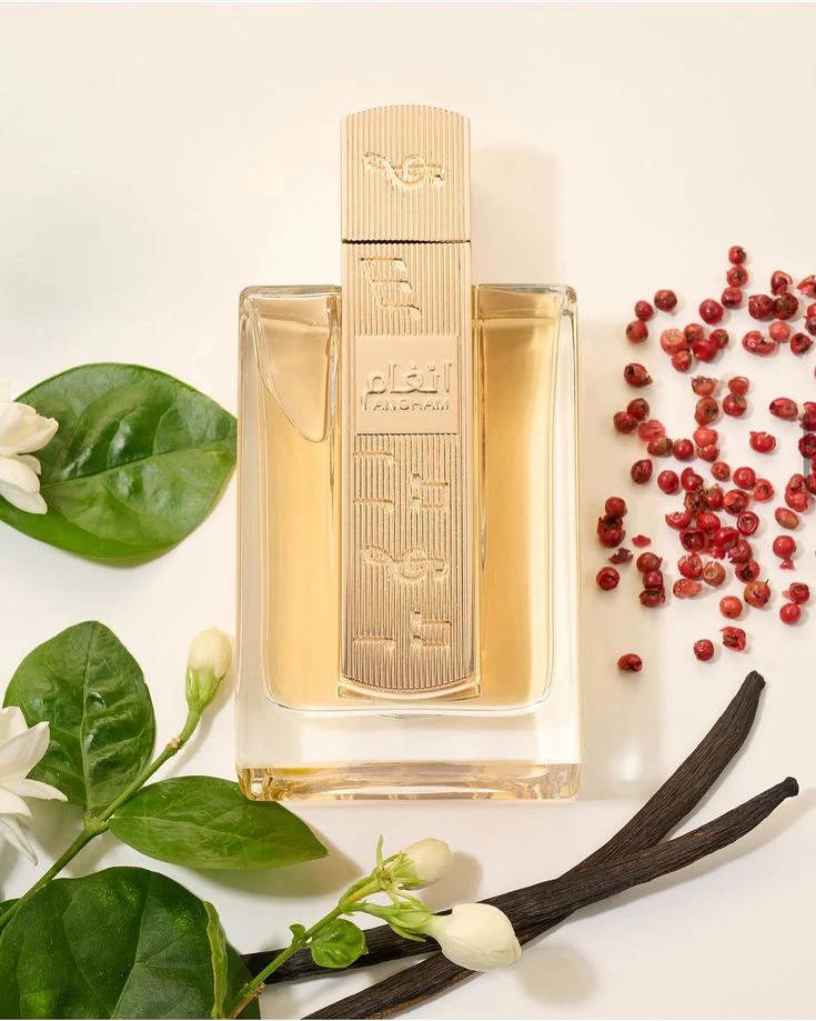 Frasco de perfume dourado com flores brancas, folhas verdes, bagas vermelhas e vagens de baunilha