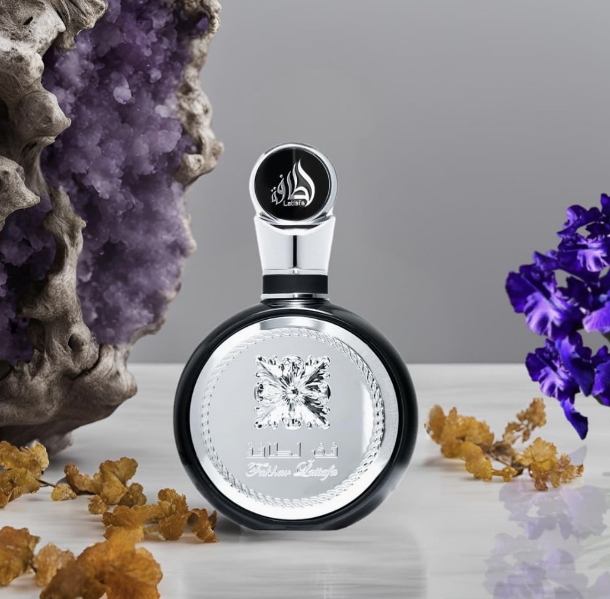 Frasco de perfume preto com etiqueta prateada e flores lilases e cristal roxo ao lado