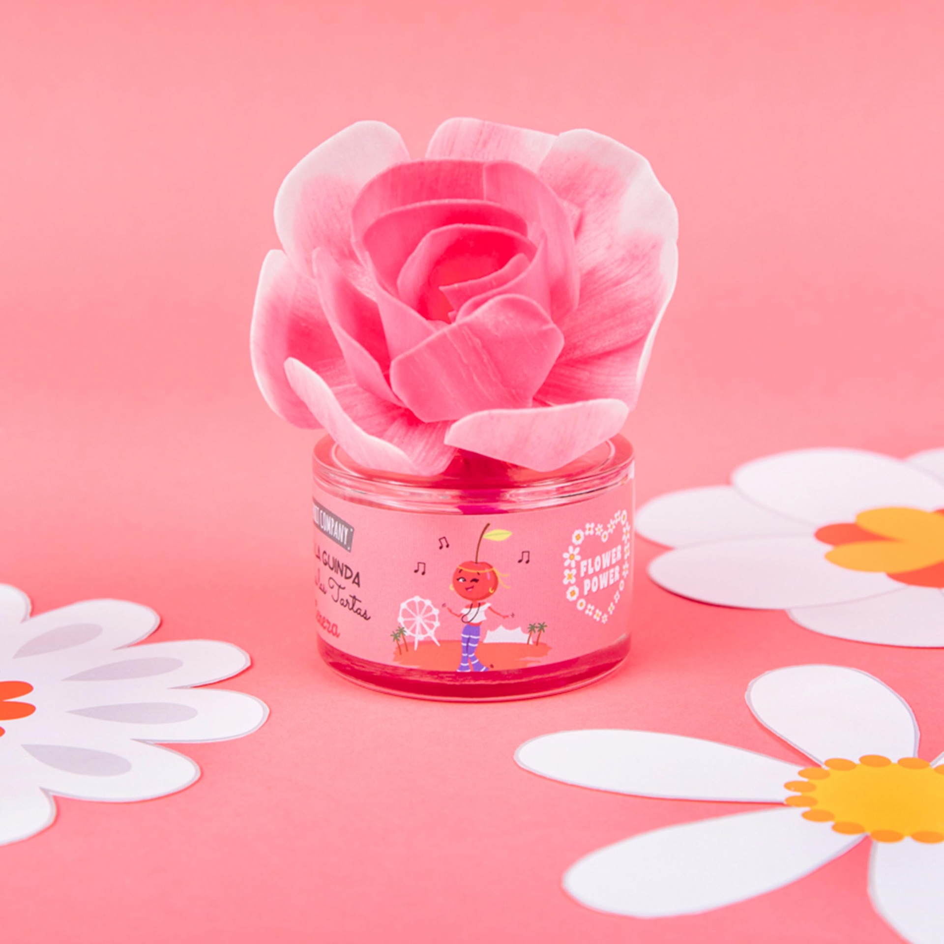 Vela em vaso de vidro decorada com flor rosa e adesivo colorido em fundo rosa com flores de papel