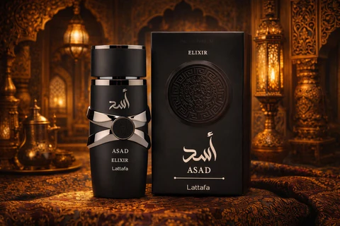Frasco e caixa de perfume negro com texto em árabe e inglês, sobre tecido decorativo em ambiente árabe iluminado.