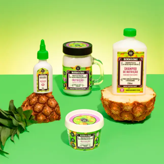 Produtos cosméticos Biozinha Case com rótulos de nutrição e shampoo, junto a abacaxis em fundo verde e amarelo.