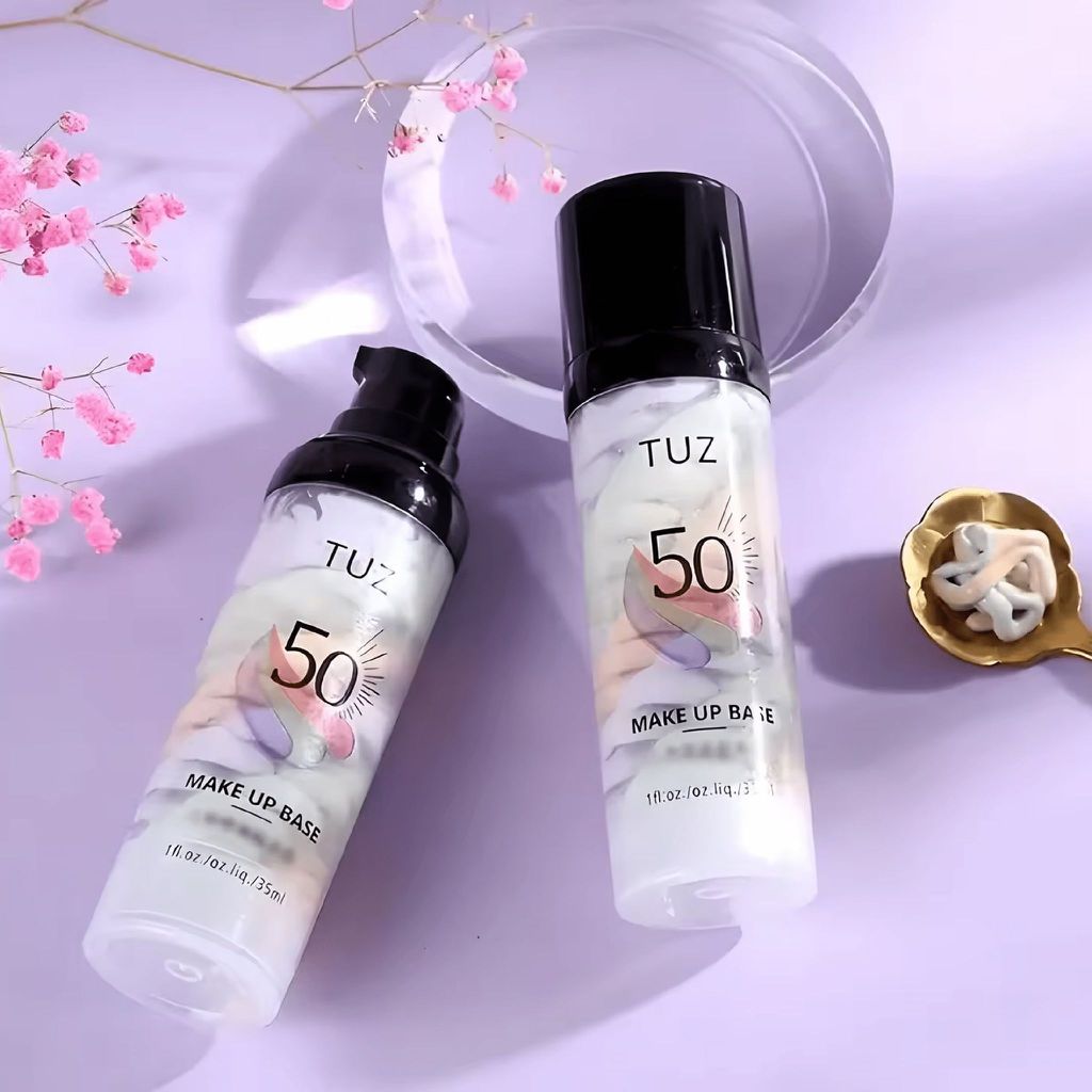 Frascos de base de maquilhagem TUZ 50 com conteúdo em espiral colorido, flores cor-de-rosa e prato dourado com amostra