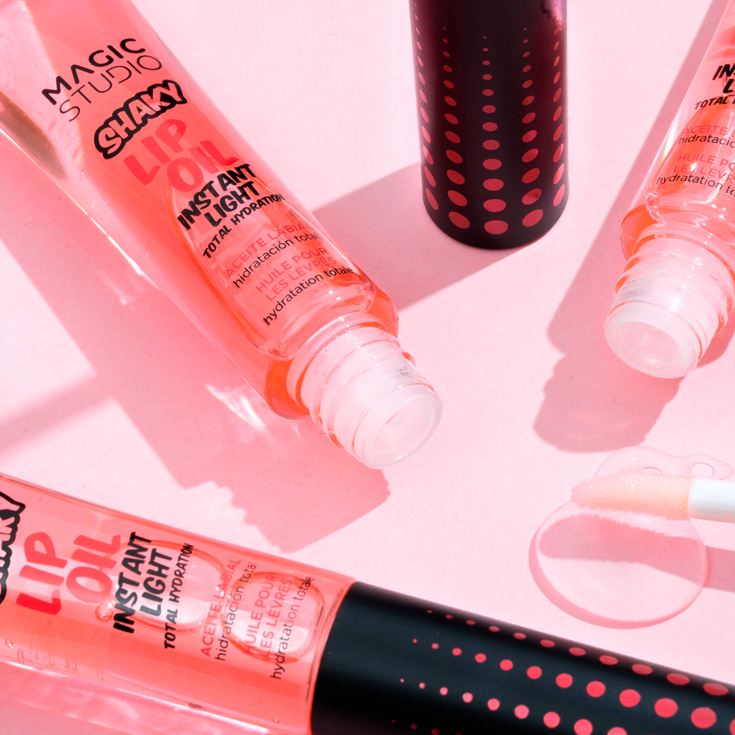 Tubos de brilho labial cor-de-rosa com texto preto e tampa preta com bolinhas cor-de-rosa