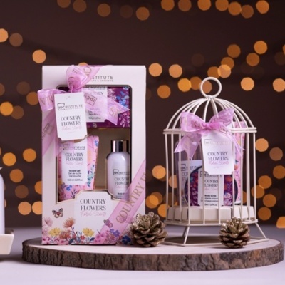 Conjunto de produtos de banho COUNTRY FLOWERS em embalagens florais rosa e branco, caixa e gaiola decorativa branca com laço rosa.