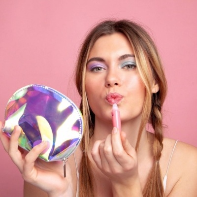 Mulher a aplicar baton com bolsinha de maquilhagem holográfica prateada