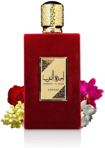 Frasco de perfume vermelho com rótulo dourado e flores ao fundo
