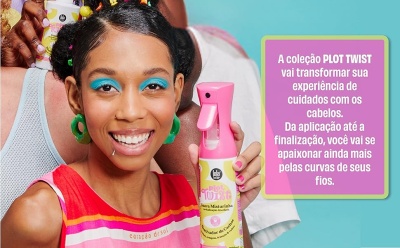 Mulher sorridente a segurar spray PLOT TWIST com maquilhagem azul e roupas coloridas