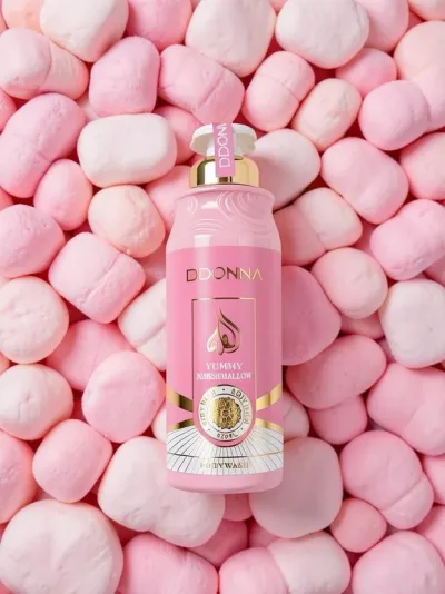 Frasco rosa de bodywash DDONNA sobre muitos marshmallows cor-de-rosa e brancos.