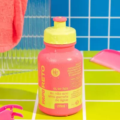 garrafa desportiva rosa e amarela sobre superfície verde e fundo azul