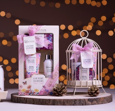 Conjunto de produtos de banho COUNTRY FLOWERS em embalagens florais rosa e branco, caixa e gaiola decorativa branca com laço rosa.