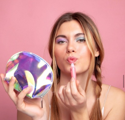 Mulher a aplicar baton com bolsinha de maquilhagem holográfica prateada