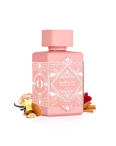 Frasco rosa de perfume Badee Al Oud com decoração geométrica e elementos naturais ao redor