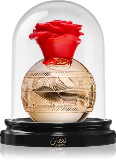 Frasco de perfume dourado com tampa vermelha em forma de rosa dentro de redoma de vidro