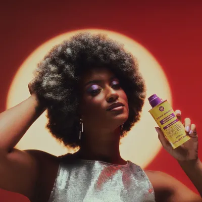 Mulher com cabelo afro espesso e vestido prateado segura shampoo amarelo