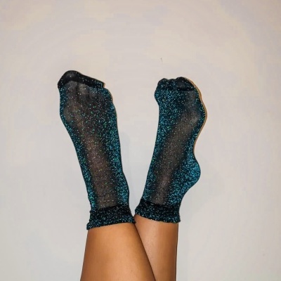 Meias transparentes pretas com brilho azul em pernas, fundo claro