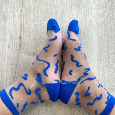 Meias transparentes com padrão azul sobre chão de madeira clara