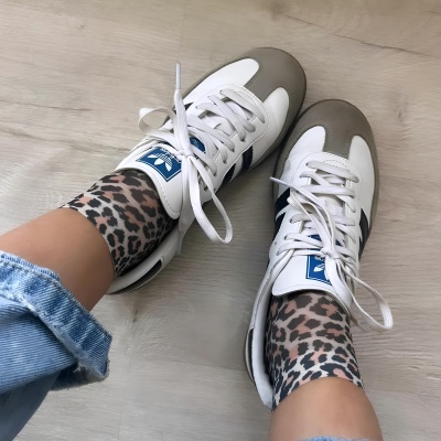 Ténis brancos e cinzentos com atacadores brancos e meias com padrão de onça