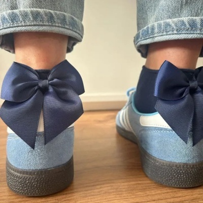 Ténis azuis com laços grandes na parte de trás, calças de ganga claras