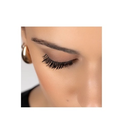 Olho feminino com pestanas postiços volumosas, sobrancelha escura e brinco dourado de argola