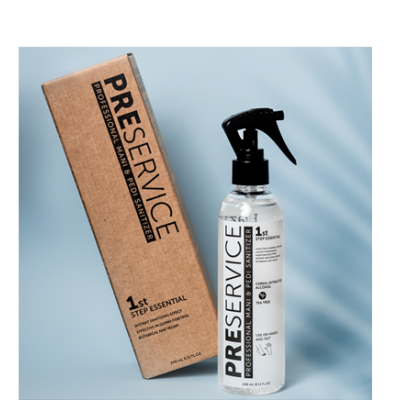 Frasco de spray transparente com texto preto e branco e embalagem castanha ao lado, fundo azul claro