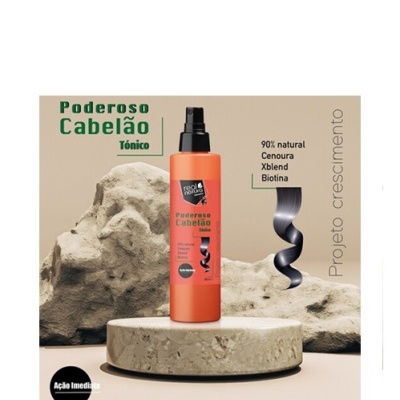 Frasco laranja de tónico para cabelo com tampa de spray preta, sobre base de pedra clara e rochas ao fundo