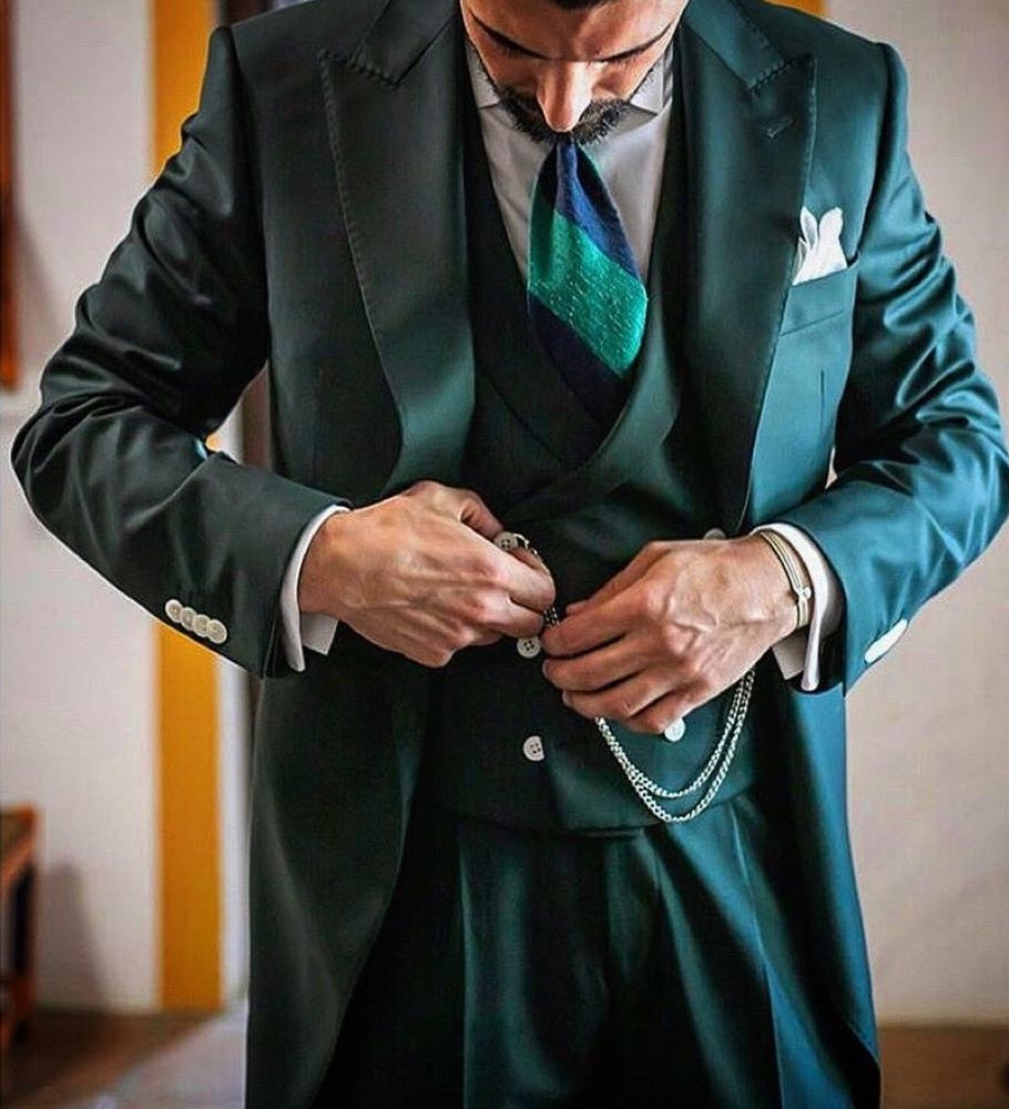 Homem a vestir fato verde escuro com gravata azul e verde