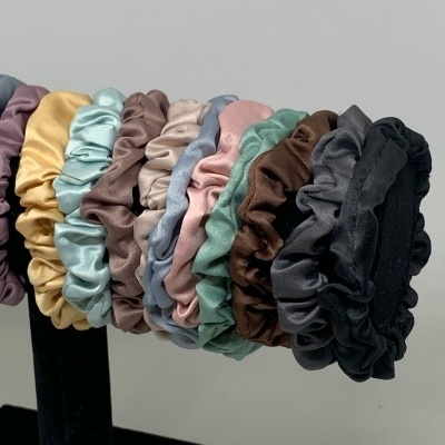 Oito elásticos de cabelo de tecido acetinado em cores sólidas numa base preta