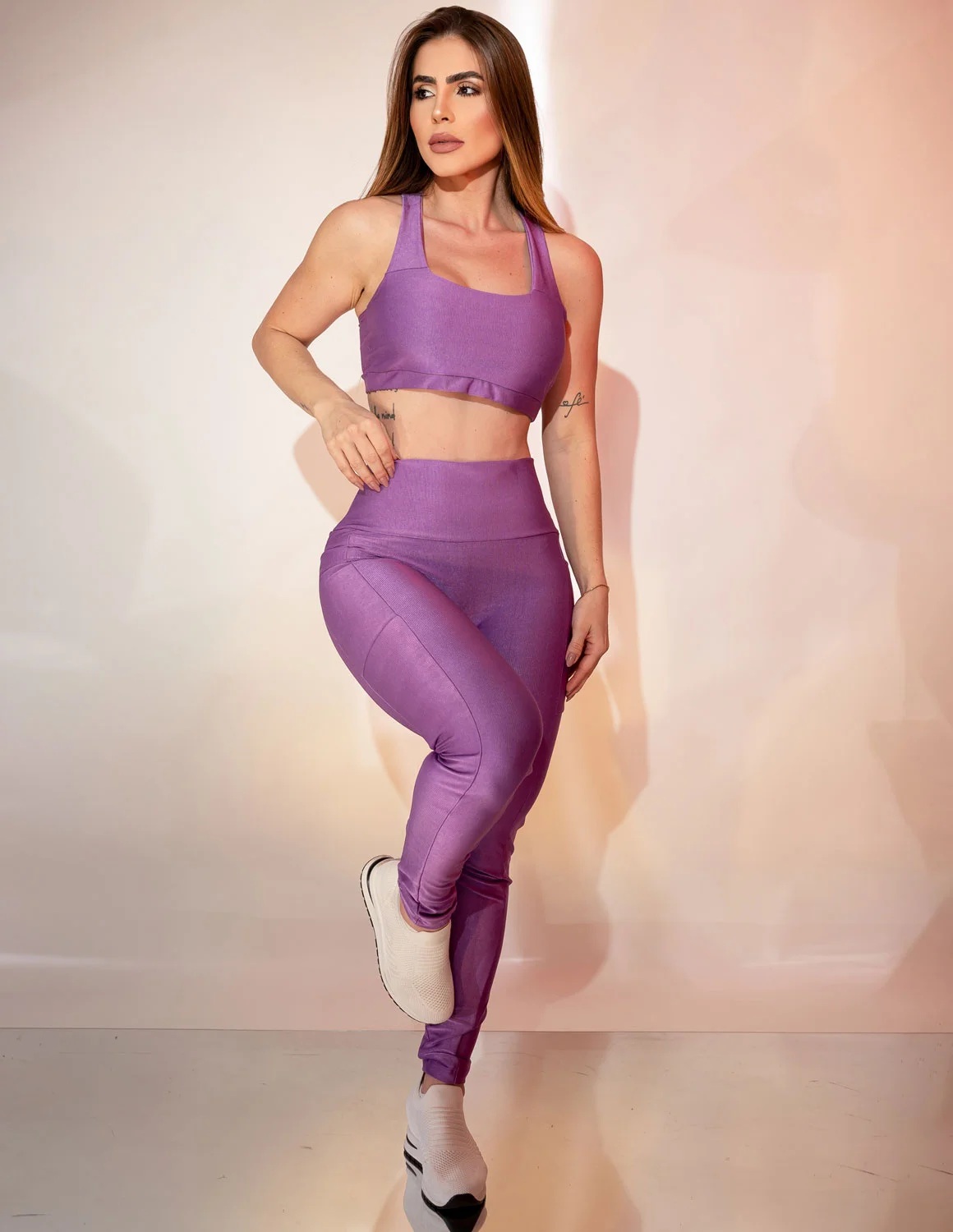 Conjunto Canelado Calça com Bolsos Laterais e Top sem Bojo para Academia Mulher com conjunto desportivo lilás e sapatilhas brancas num fundo claro