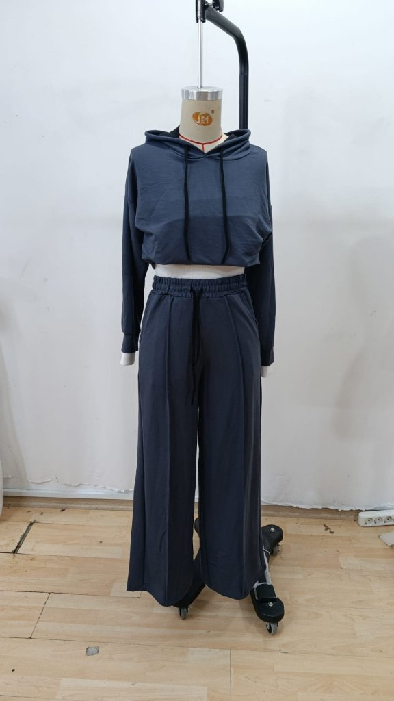 Conjunto desportivo azul escuro com hoodie cropped e calças largas em manequim.