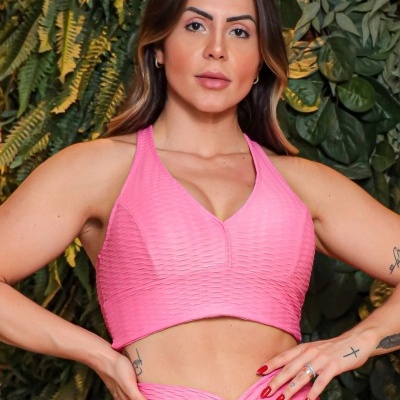 Top cropped e calças de desporto rosa textoizado em mulher com tatuagens e unhas vermelhas