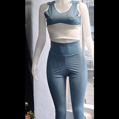 Conjunto roupa desportiva azul claro e branco em manequim junto a janela